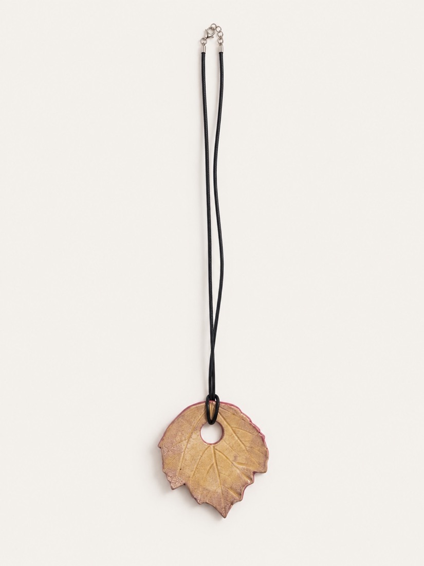 Collar de cordón negro con un colgante de hoja en ocre y rosa
