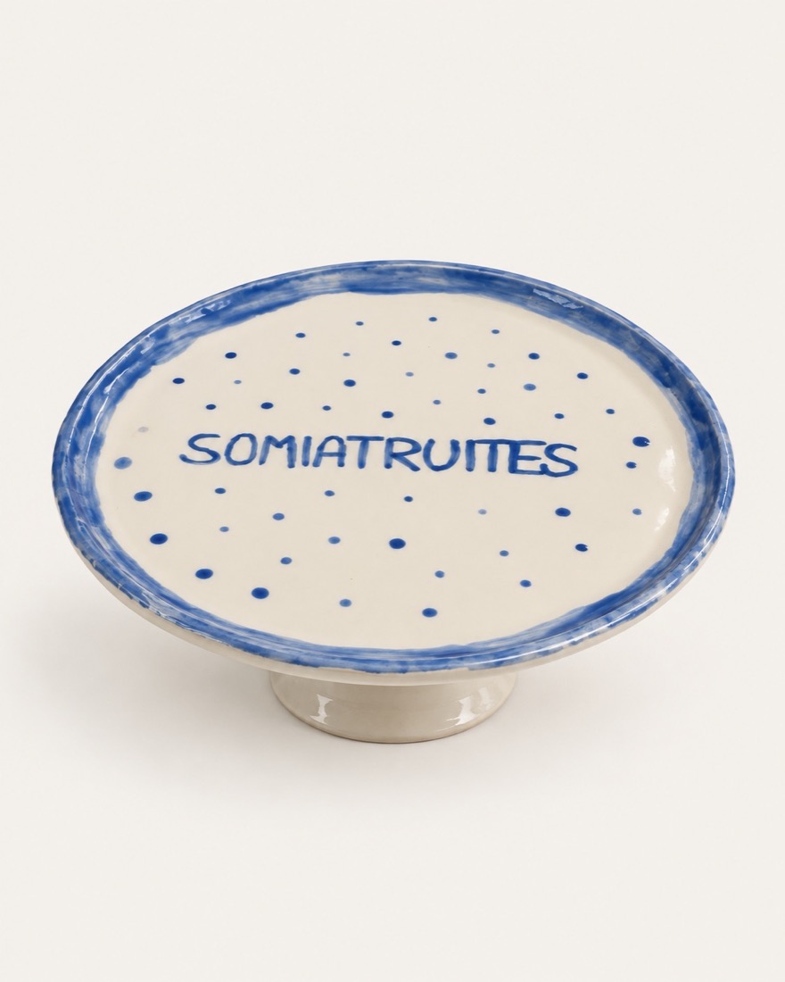 Soporte de tarta con pie, borde azul, puntos azules y la palabra Somiatruites pintada