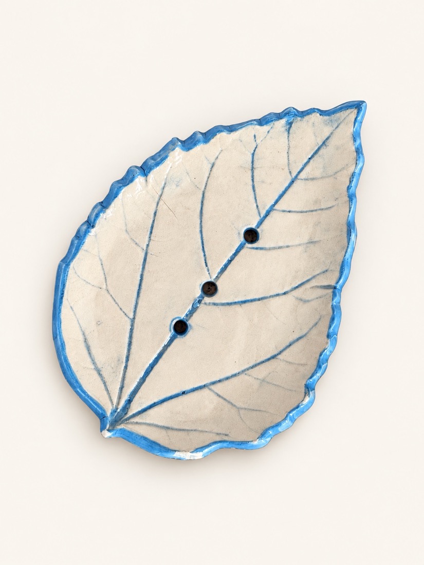 Jabonera con forma de hoja, nervios y borde en azul y agujeros de drenaje