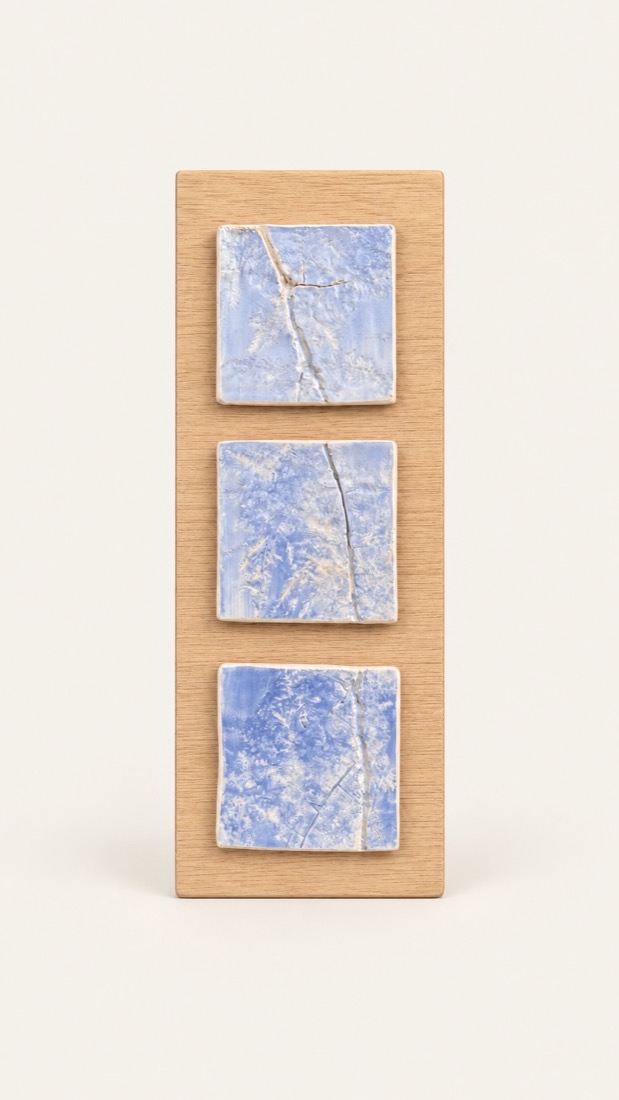 Tres azulejos con impresiones vegetales en azul, montados sobre madera